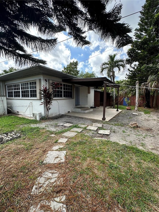 view of front of property featuring an attached carport, fence, driveway, stucco siding, and a front yard