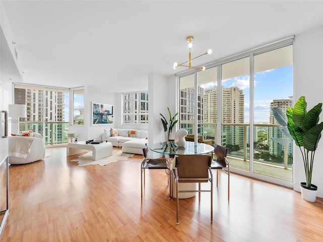 dining area with expansive windows, light hardwood / wood-style floors, and an inviting chandelier