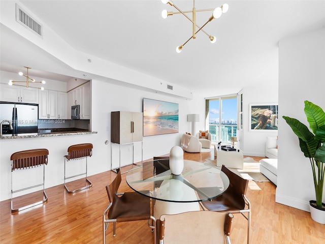 dining area featuring light wood-type flooring and an inviting chandelier