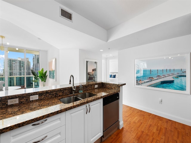 kitchen with white cabinets, dark stone counters, sink, dishwasher, and light hardwood / wood-style floors