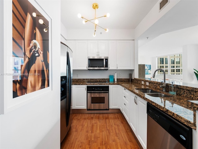 kitchen with dark stone counters, stainless steel appliances, sink, light hardwood / wood-style floors, and white cabinetry