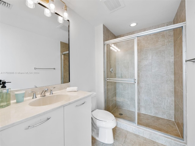 bathroom featuring tile patterned floors, vanity, toilet, and a shower with shower door