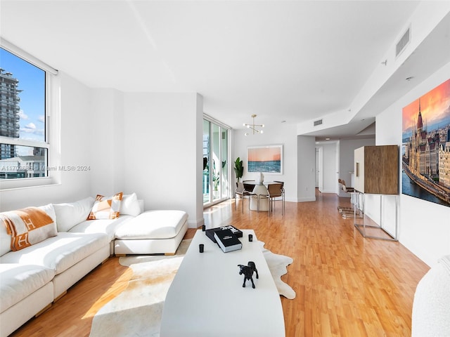 living room with light hardwood / wood-style flooring, a wealth of natural light, and a notable chandelier