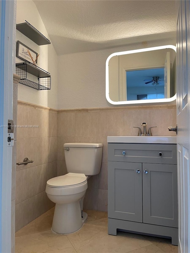 bathroom with vanity, a textured ceiling, tile patterned floors, and tile walls