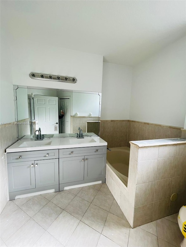 bathroom featuring tile patterned floors, a bathing tub, vanity, and tile walls