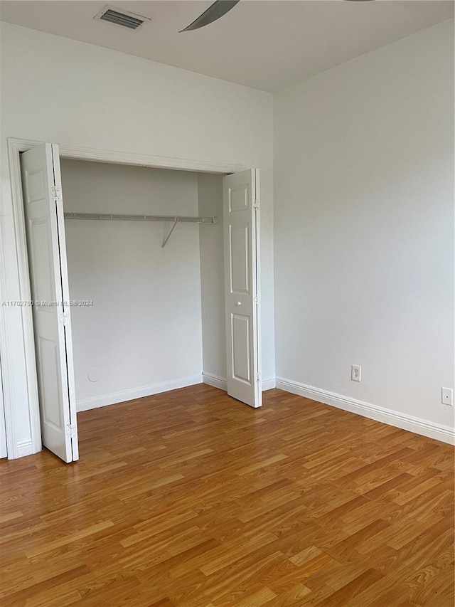 unfurnished bedroom with hardwood / wood-style floors, ceiling fan, and a closet