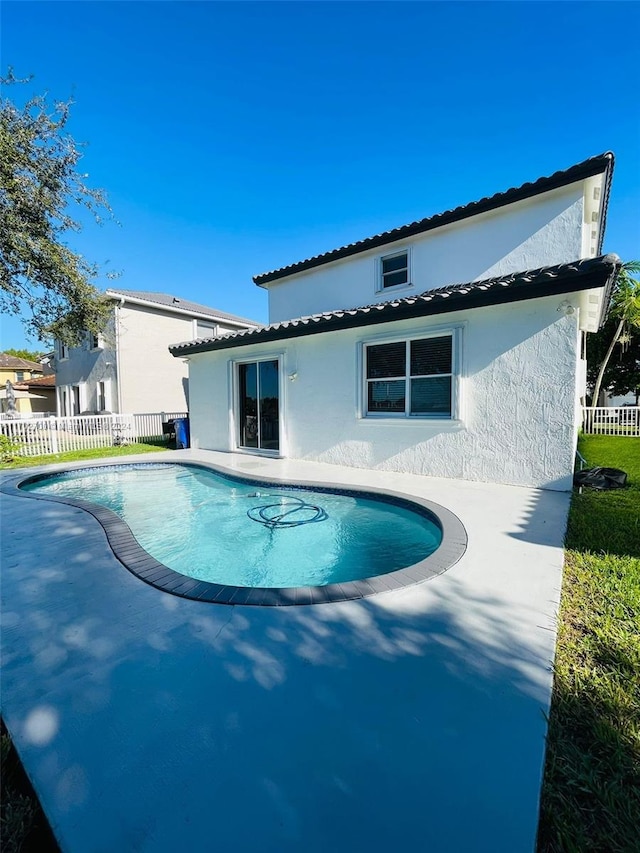 rear view of property with a fenced in pool and a patio