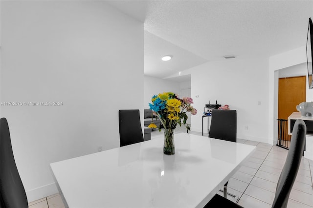 tiled dining room featuring lofted ceiling and a textured ceiling