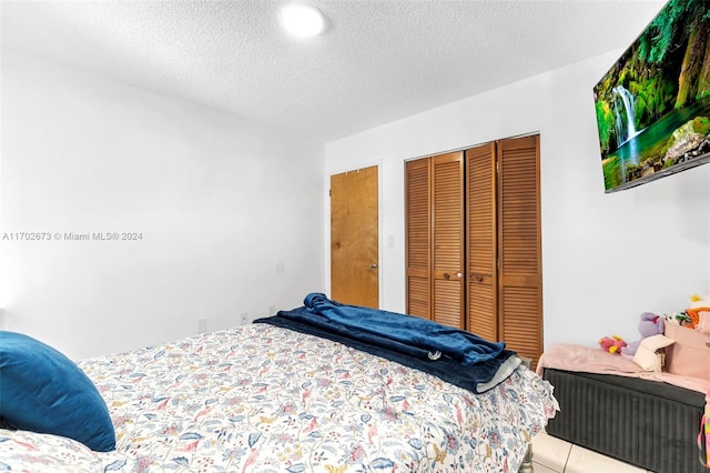 bedroom with light tile patterned floors, a textured ceiling, and a closet