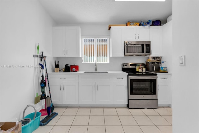 kitchen featuring white cabinetry, sink, light tile patterned flooring, and appliances with stainless steel finishes