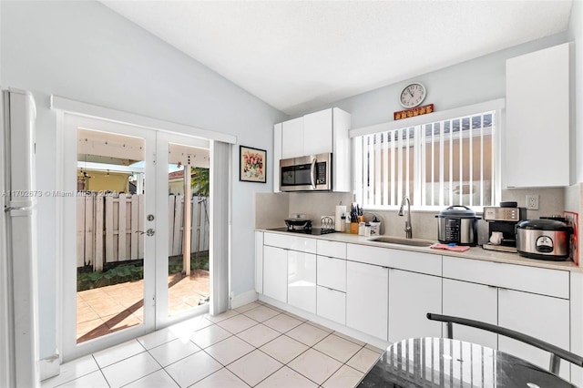 kitchen with gas cooktop, tasteful backsplash, vaulted ceiling, sink, and white cabinetry