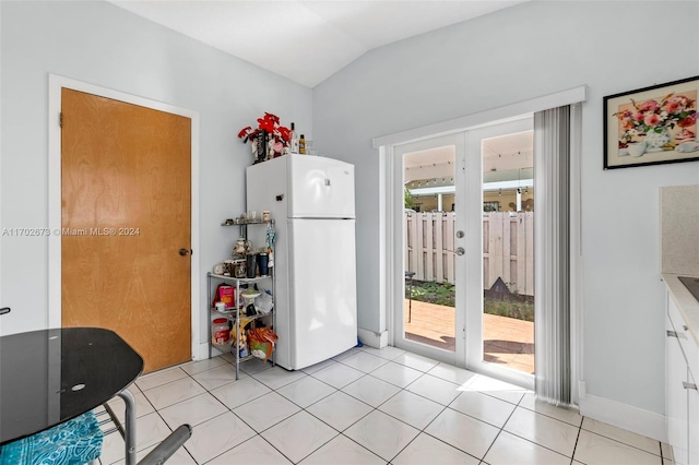 kitchen featuring white refrigerator, lofted ceiling, white cabinetry, and light tile patterned floors