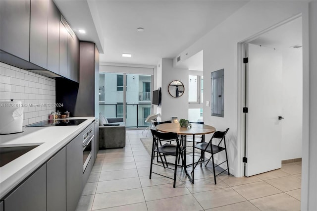 kitchen featuring stainless steel oven, black electric stovetop, tasteful backsplash, and light tile patterned flooring