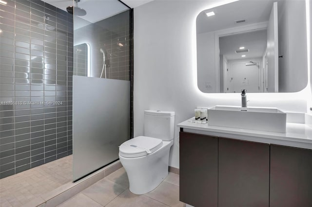 bathroom with tile patterned floors, toilet, vanity, and tiled shower