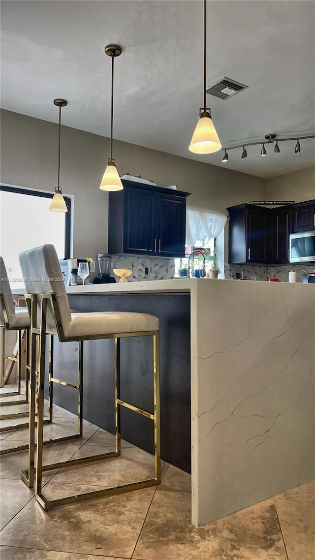 kitchen featuring pendant lighting, blue cabinets, and tasteful backsplash