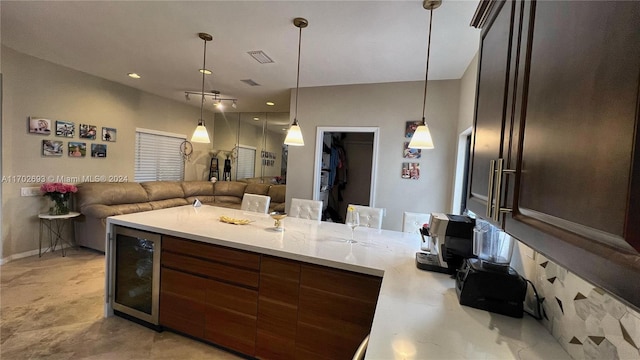 kitchen with pendant lighting, dark brown cabinetry, and beverage cooler