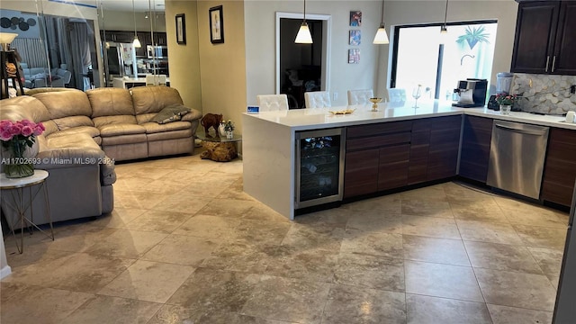 kitchen with beverage cooler, stainless steel appliances, kitchen peninsula, pendant lighting, and dark brown cabinets