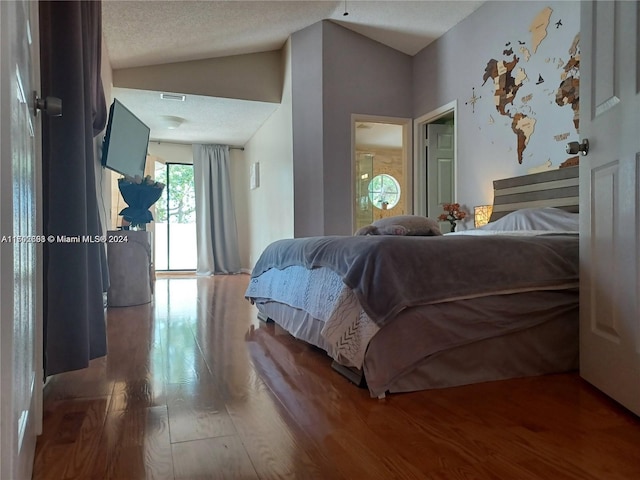 bedroom featuring hardwood / wood-style flooring, a textured ceiling, and vaulted ceiling