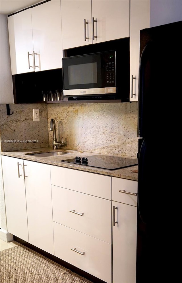 kitchen featuring decorative backsplash, white cabinetry, sink, and black appliances