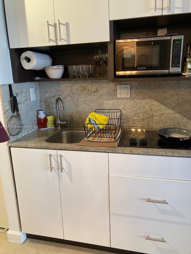 19201 Collins Ave Unit 726, Sunny Isles Beach, FL 33160 - kitchen featuring stainless steel microwave, white cabinetry, black electric cooktop, backsplash, and open shelves