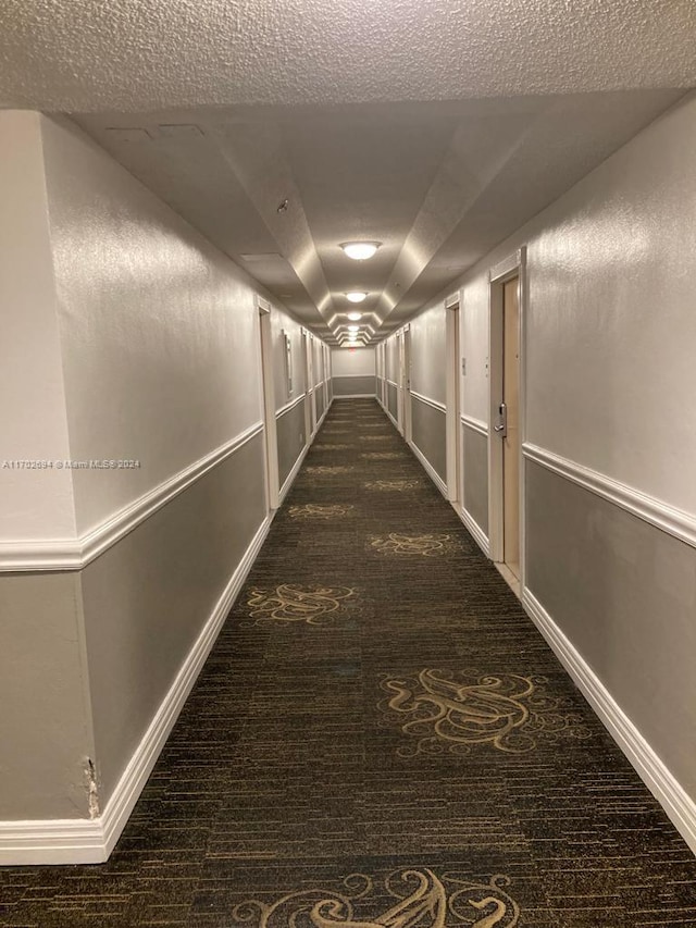 19201 Collins Ave Unit 726, Sunny Isles Beach, FL 33160 - hallway featuring dark colored carpet and a textured ceiling