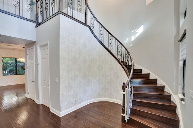 stairway with hardwood / wood-style flooring and a high ceiling