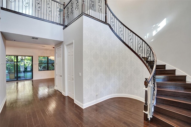 staircase with a towering ceiling and hardwood / wood-style flooring