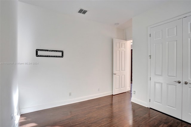 unfurnished bedroom featuring a closet and dark hardwood / wood-style flooring