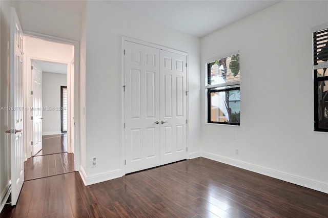 unfurnished bedroom featuring a closet and dark hardwood / wood-style flooring