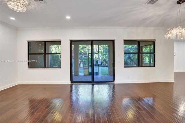 empty room with dark hardwood / wood-style floors, an inviting chandelier, and crown molding