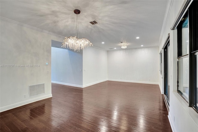 empty room featuring a chandelier, dark hardwood / wood-style floors, and crown molding