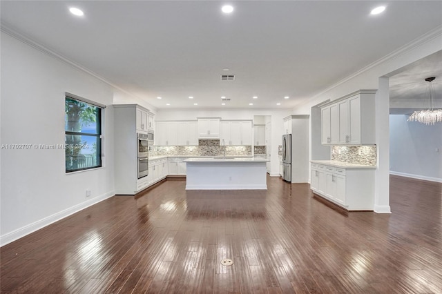 kitchen with pendant lighting, dark hardwood / wood-style floors, ornamental molding, and appliances with stainless steel finishes