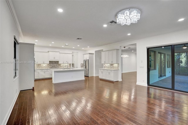 unfurnished living room featuring sink, ornamental molding, dark hardwood / wood-style floors, and an inviting chandelier