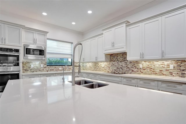 kitchen featuring backsplash, stainless steel appliances, crown molding, and sink