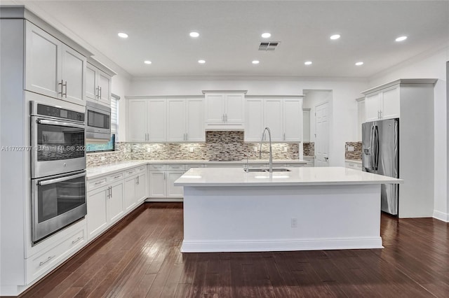 kitchen featuring dark wood-type flooring, sink, an island with sink, tasteful backsplash, and stainless steel appliances