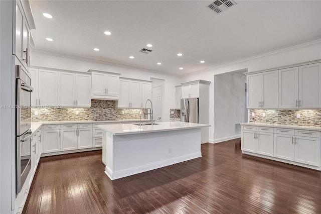 kitchen with dark hardwood / wood-style flooring, stainless steel appliances, sink, a center island with sink, and white cabinetry