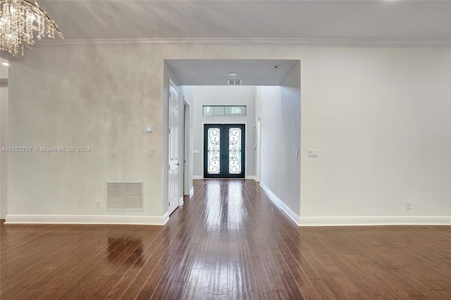 entrance foyer featuring a notable chandelier, dark hardwood / wood-style flooring, ornamental molding, and french doors