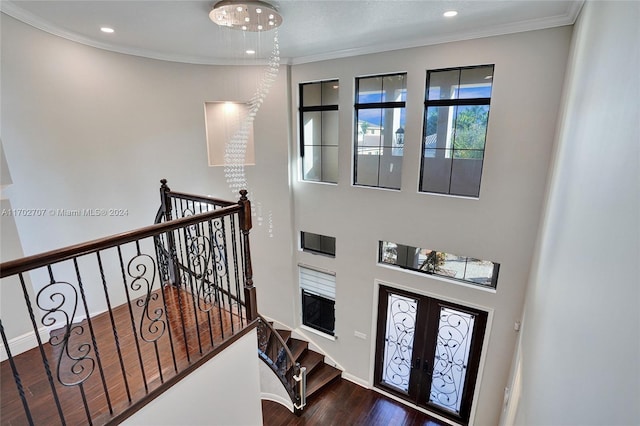 foyer entrance featuring dark hardwood / wood-style floors, ornamental molding, a chandelier, and french doors