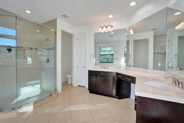 bathroom featuring tile patterned flooring, vanity, toilet, and a shower with shower door