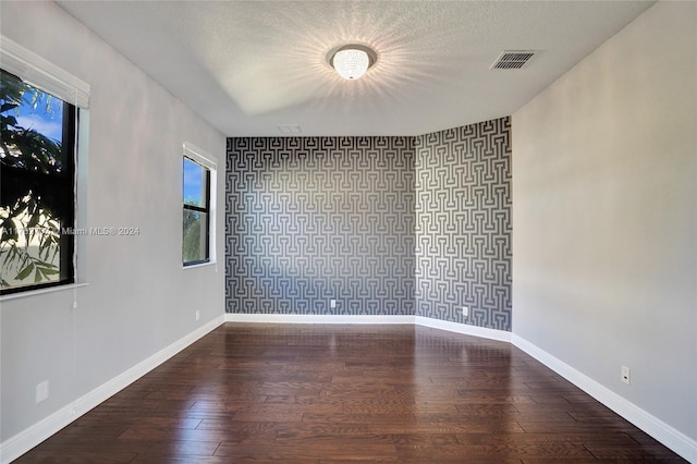 unfurnished room featuring wood-type flooring and a textured ceiling