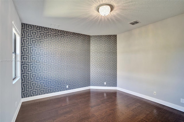 empty room featuring a textured ceiling and dark wood-type flooring