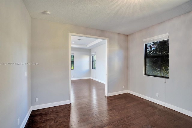 spare room with a textured ceiling and dark hardwood / wood-style flooring