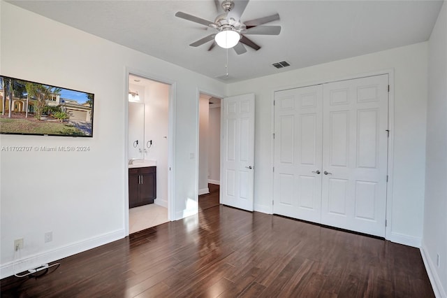 unfurnished bedroom featuring ensuite bath, ceiling fan, a closet, and dark hardwood / wood-style floors