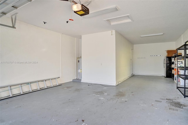 garage featuring black refrigerator and a garage door opener