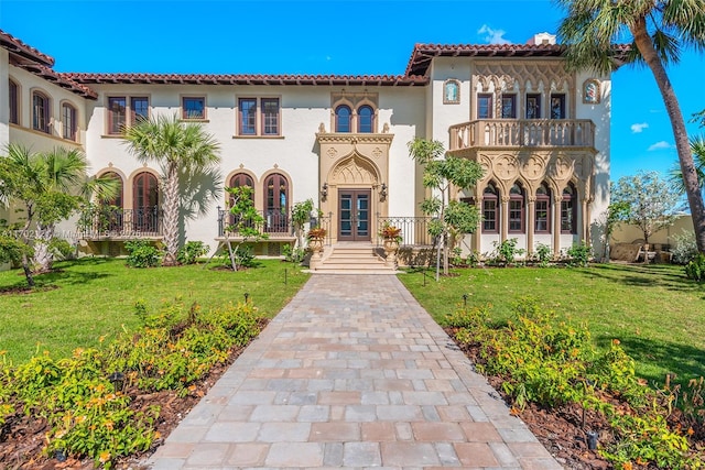 mediterranean / spanish house featuring a balcony, a front yard, and french doors