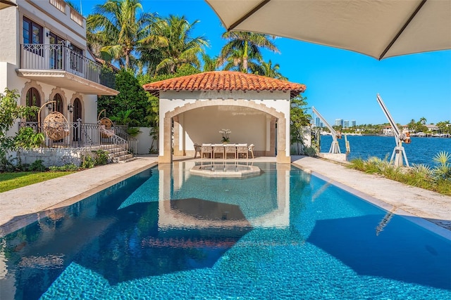 view of pool featuring a water view, a patio area, and an outbuilding