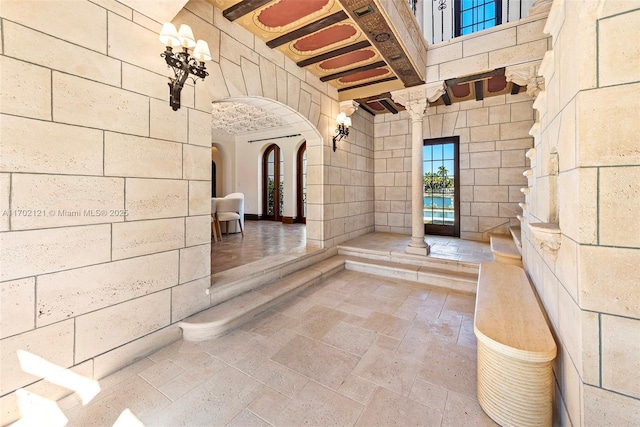 interior space with beam ceiling, a towering ceiling, and decorative columns