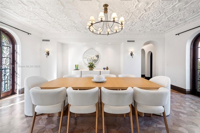 dining room featuring a notable chandelier, crown molding, and parquet flooring