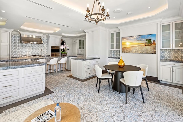 dining area with crown molding, an inviting chandelier, and a tray ceiling