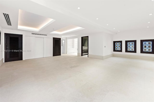 unfurnished room with built in shelves and a tray ceiling